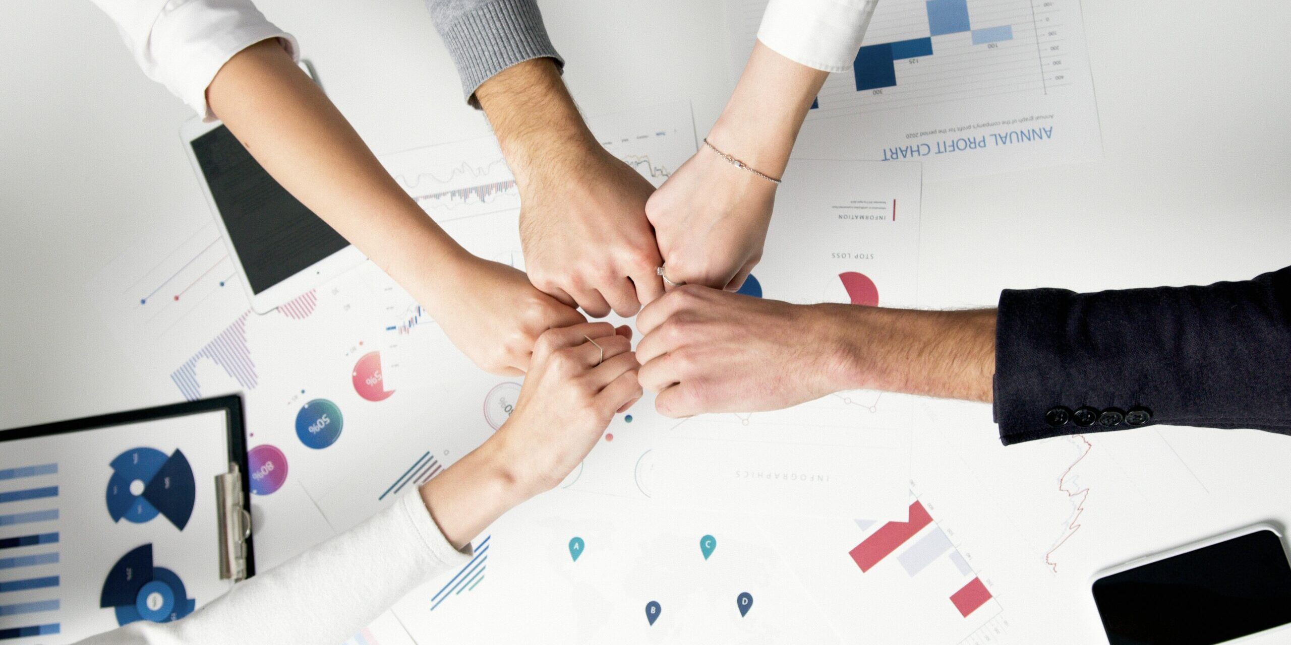 How-Smart-IT-Boosts-Employee-Morale-and-Keeps-Your-Best-People-scaled.jpg Free Colleagues celebrate success with a fist bump over financial charts depicting teamwork and unity. Stock Photo