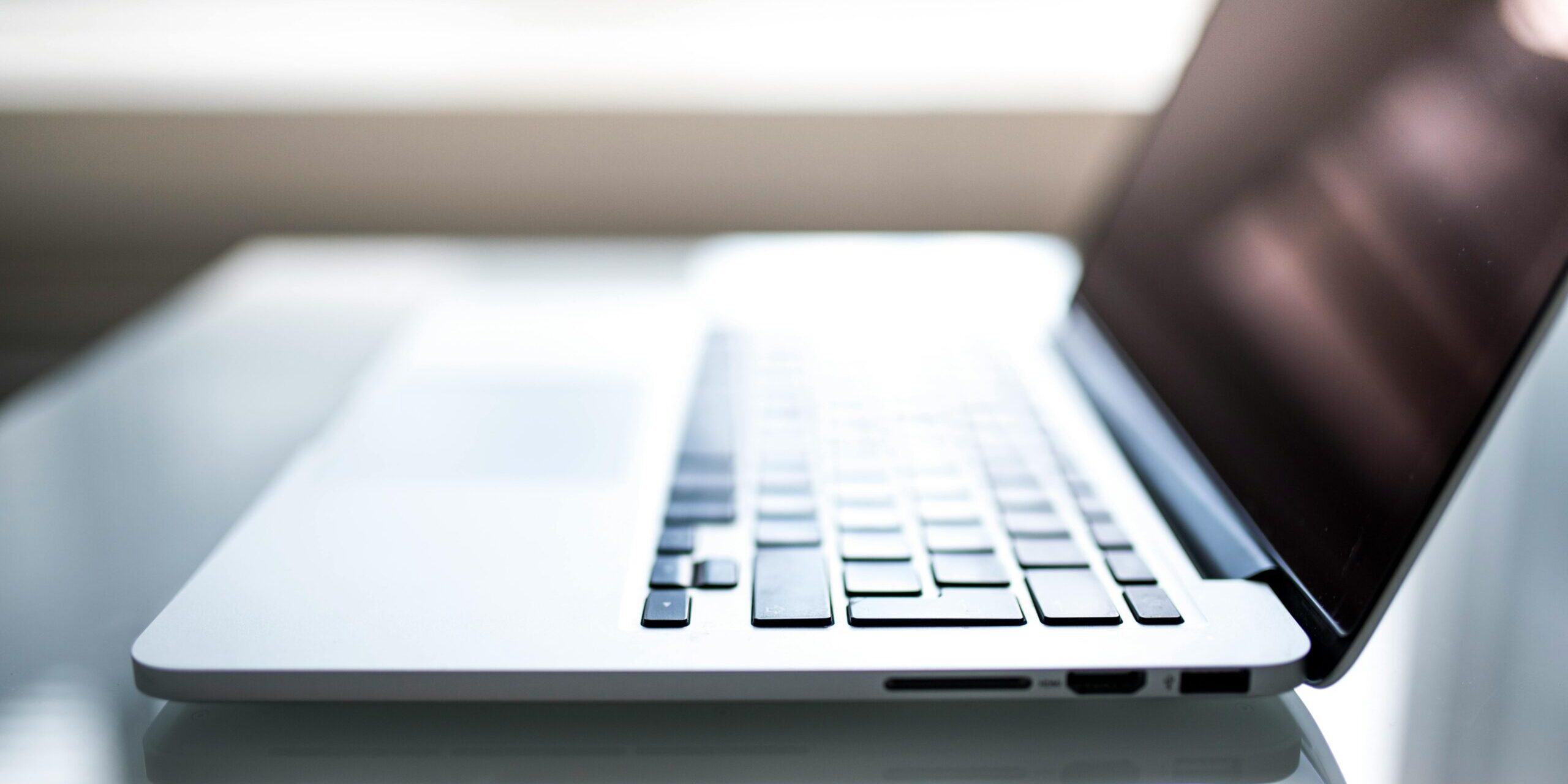 Free Elegant side view of a laptop on a glossy table with natural lighting indoors. Stock Photo