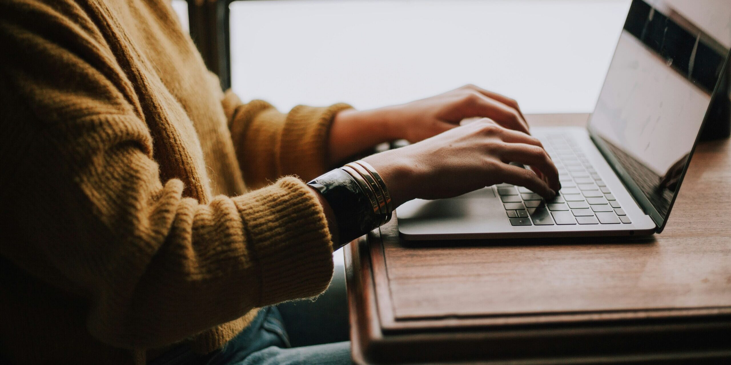 christin-hume-mfB1B1s4sMc-unsplash-scaled.jpg person sitting front of laptop